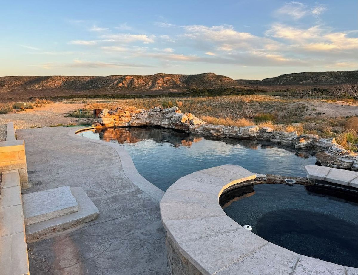 Ein Poolbereich mit Steintreppen und Blick auf eine hügelige Landschaft.