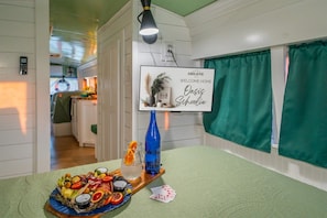 Een kamer met een bed, een nachtkastje met een dienblad eten en een bord met de tekst 'Welkom thuis', en uitzicht op een keukenhoek.