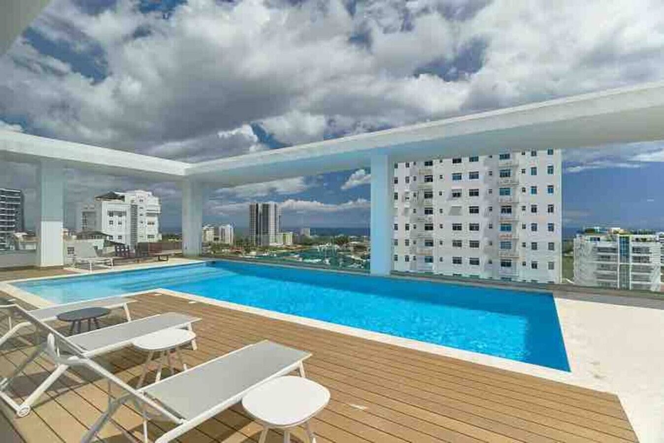 Una piscina en la azotea con sillas de descanso y vistas a la ciudad.