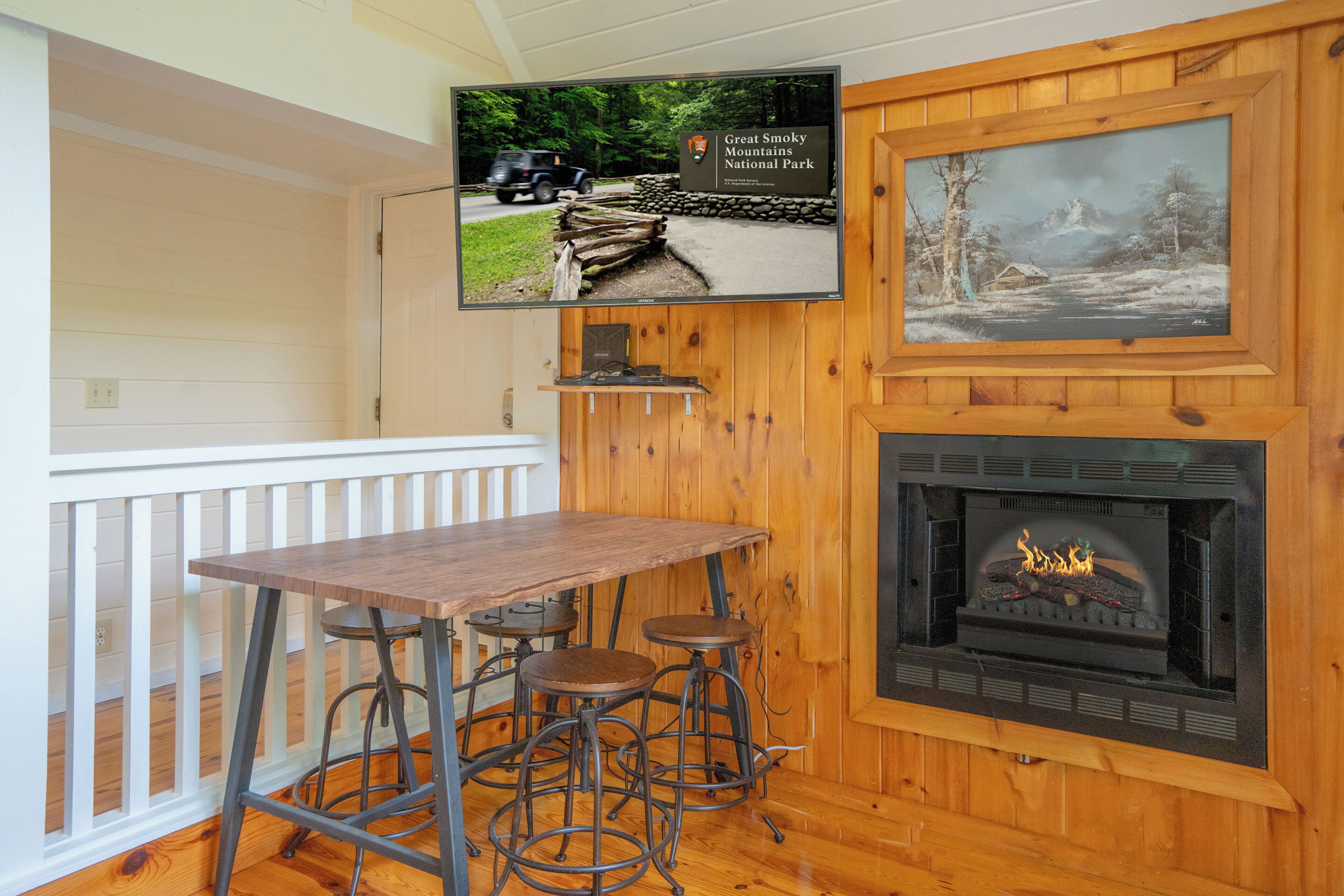 Een houten interieur met een televisie waarop Nationaal Park Great Smoky Mountains wordt weergegeven, een open haard en een bar met krukjes.