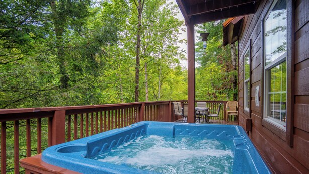 A hot tub on a wooden deck with a view of a forest.