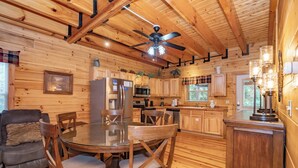 Une cuisine chaleureuse, aménagée dans le style d’un chalet, avec des murs en bois, une table à manger et des chaises.