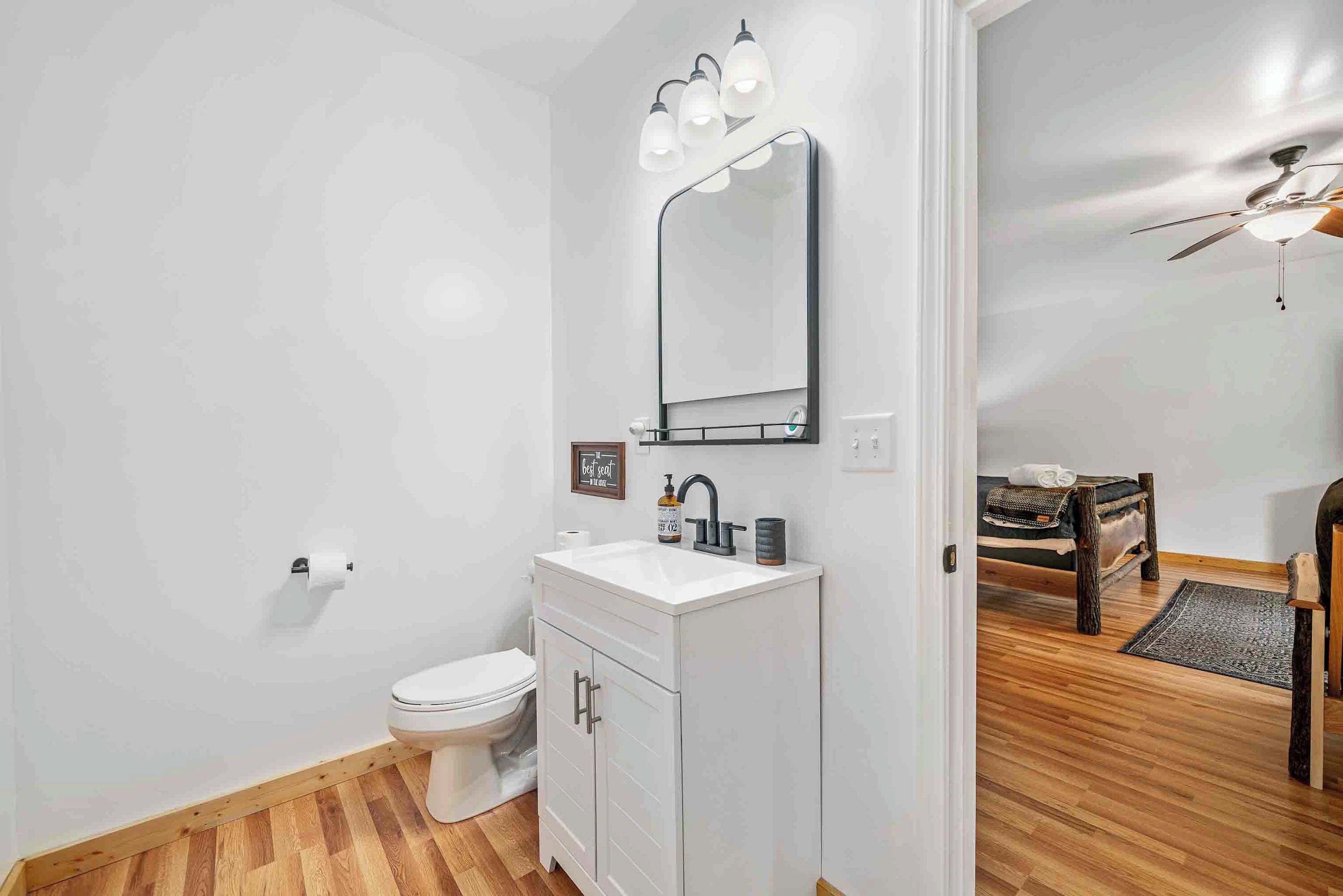 Ein Badezimmer mit weißem Waschtisch, Toilette und Deckenventilator.