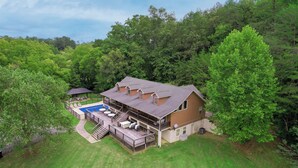 A large house with a deck, a swimming pool, and a covered patio area. - Keaton's Firefly Meadow: OutdoorPool*HotTub*Games*Wifi*FirePit*Yard*Large Groups (Sevierville)