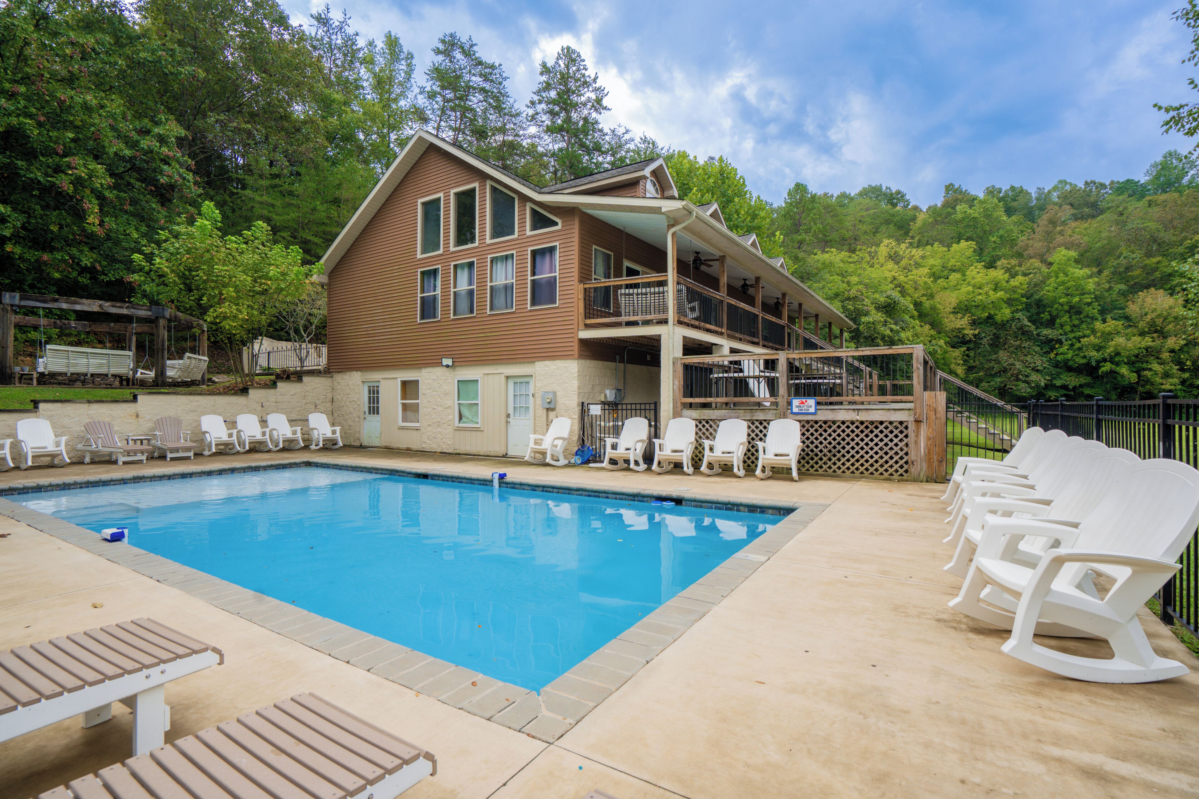 A pool area with lounge chairs and a wooden building with a balcony.