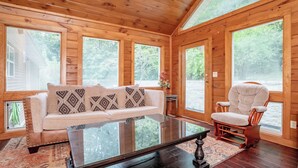 A wooden cabin interior with a sofa, armchair, and coffee table. - Keaton's Firefly Meadow: OutdoorPool*HotTub*Games*Wifi*FirePit*Yard*Large Groups (Sevierville)