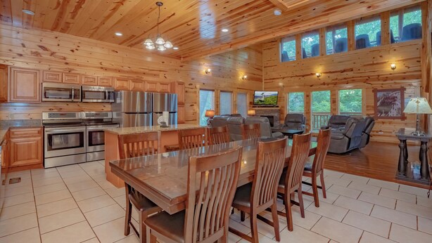 Una cocina amplia con electrodomésticos modernos, un comedor con sillas de madera y una sala de estar acogedora con chimenea.