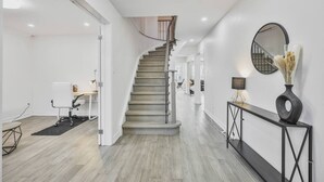 Et moderne interiør med en trappe, et skrivebord med lampe og et konsolbord med en vase.