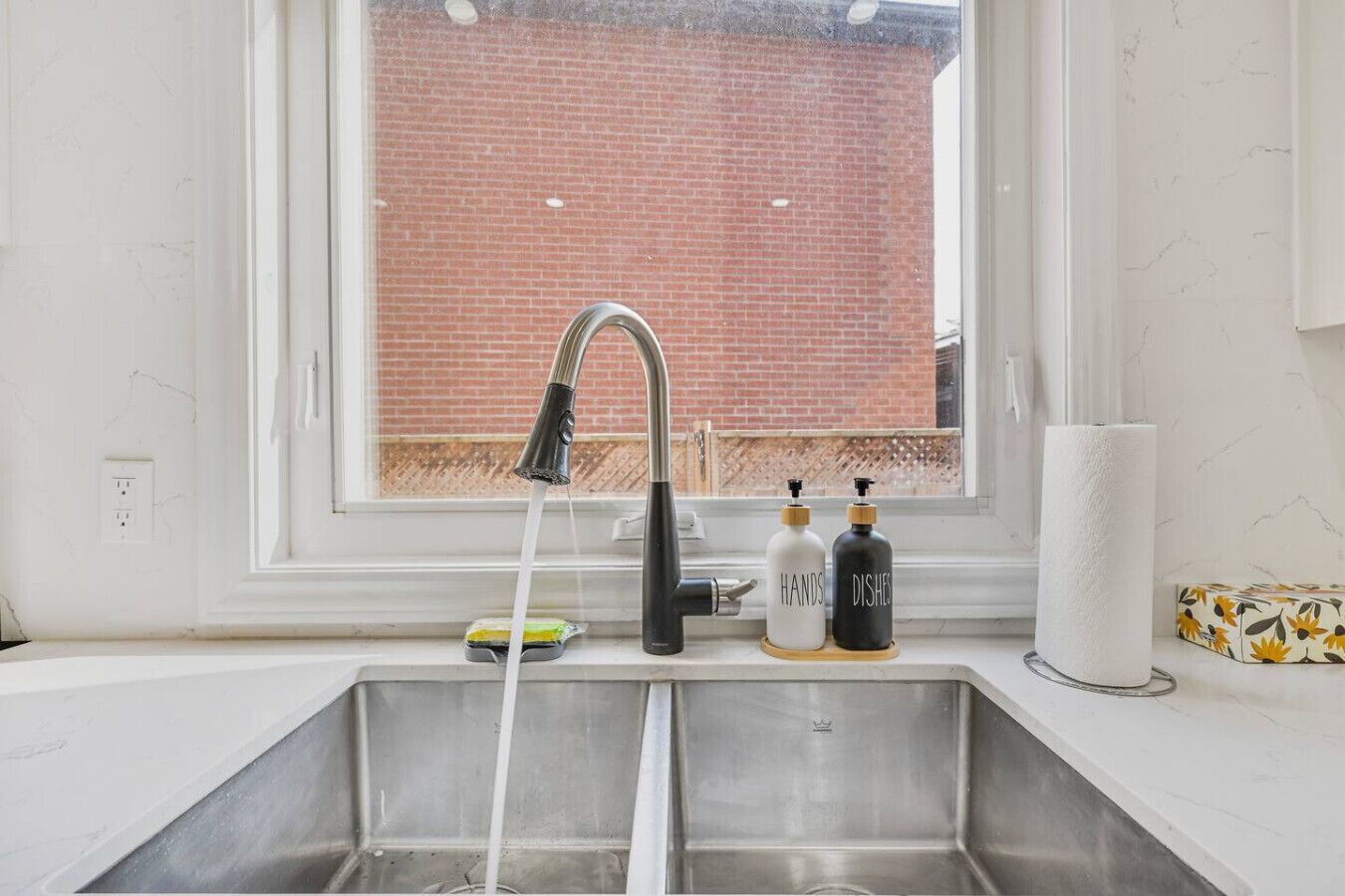 A kitchen with a stainless steel sink, a faucet, and two soap dispensers.