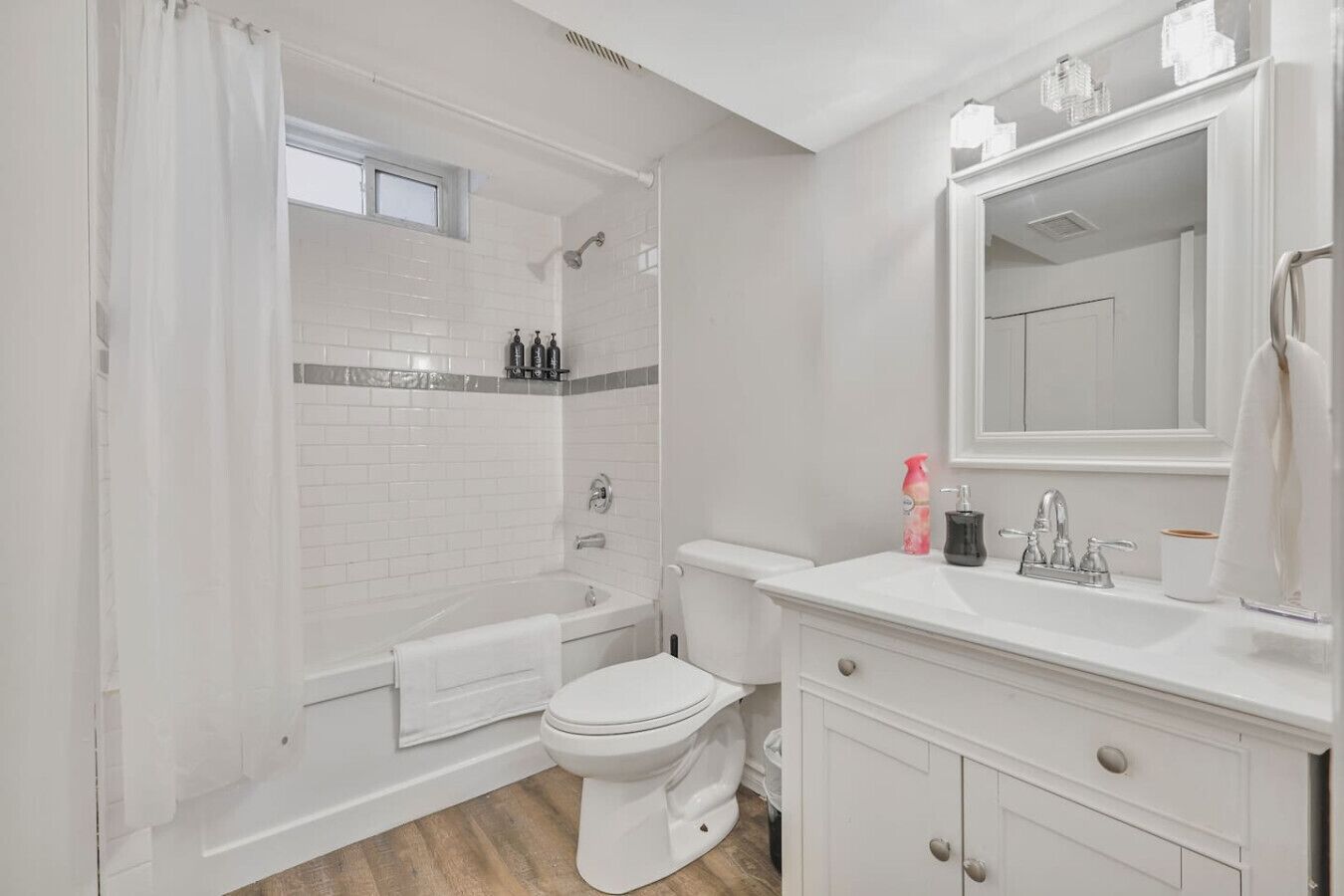 A bathroom with a bathtub, toilet, and vanity with a mirror.