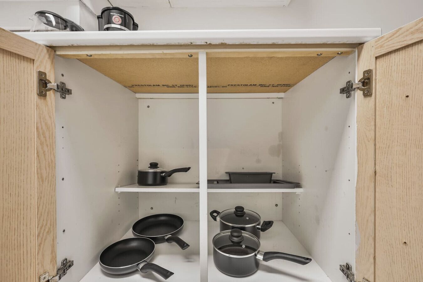 A kitchen cabinet with two shelves, each holding cookware.