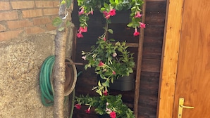 Una puerta de madera con manija de bronce, un muro de ladrillo y un árbol con flores rosadas.