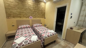 Habitación de hotel con dos camas, baño y un escritorio pequeño.