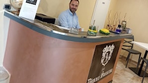 Una recepción con un letrero que dice "Bimonia Saracena". Hay cuadros enmarcados en la pared, un globo terráqueo y un arreglo floral sobre el mostrador.