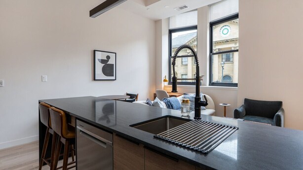 A modern kitchen with a central island, a built-in oven, and a window with a view of the city.