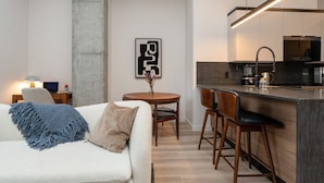 Une cuisine moderne avec un coin bar, une table à manger avec des chaises et un canapé agrémenté d’un plaid.
