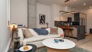 Un salon moderne avec un canapé, une table basse et un coin cuisine à l’arrière-plan.