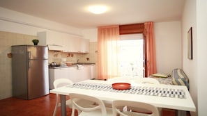 Une cuisine de taille réduite équipée d’un réfrigérateur, d’une cuisinière et d’une table à manger avec des chaises.