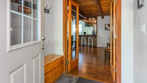 Un intérieur en bois avec un espace cuisine visible à travers une porte ouverte.