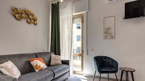 A modern living room with a grey sofa, a blue armchair, and a small round table. - Palazzo Belvedere Chianciano Terme (Chianciano Terme)