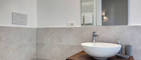 Ein modernes Badezimmer mit Waschbecken, Ablagefläche und Toilette in Weiß.
