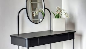 A black vanity with a mirror and a white vase with flowers. - Palazzo Belvedere Chianciano Terme (Chianciano Terme)