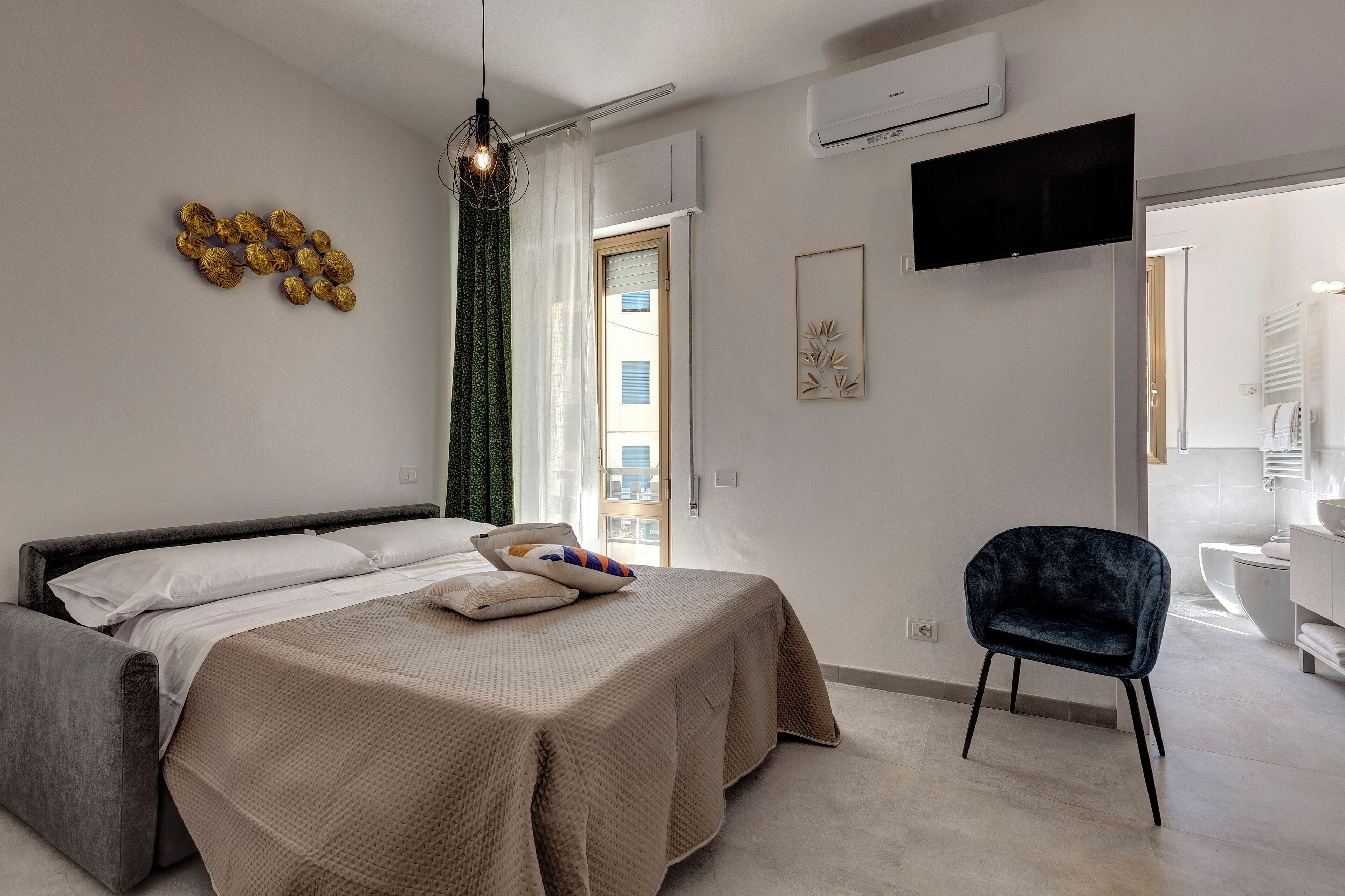 A modern bedroom with a bed, a chair, and a TV on the wall.