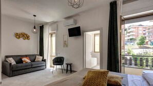 A modern hotel room with a large bed, a sofa, a TV, and a balcony with a view of the city. - Palazzo Belvedere Chianciano Terme (Chianciano Terme)