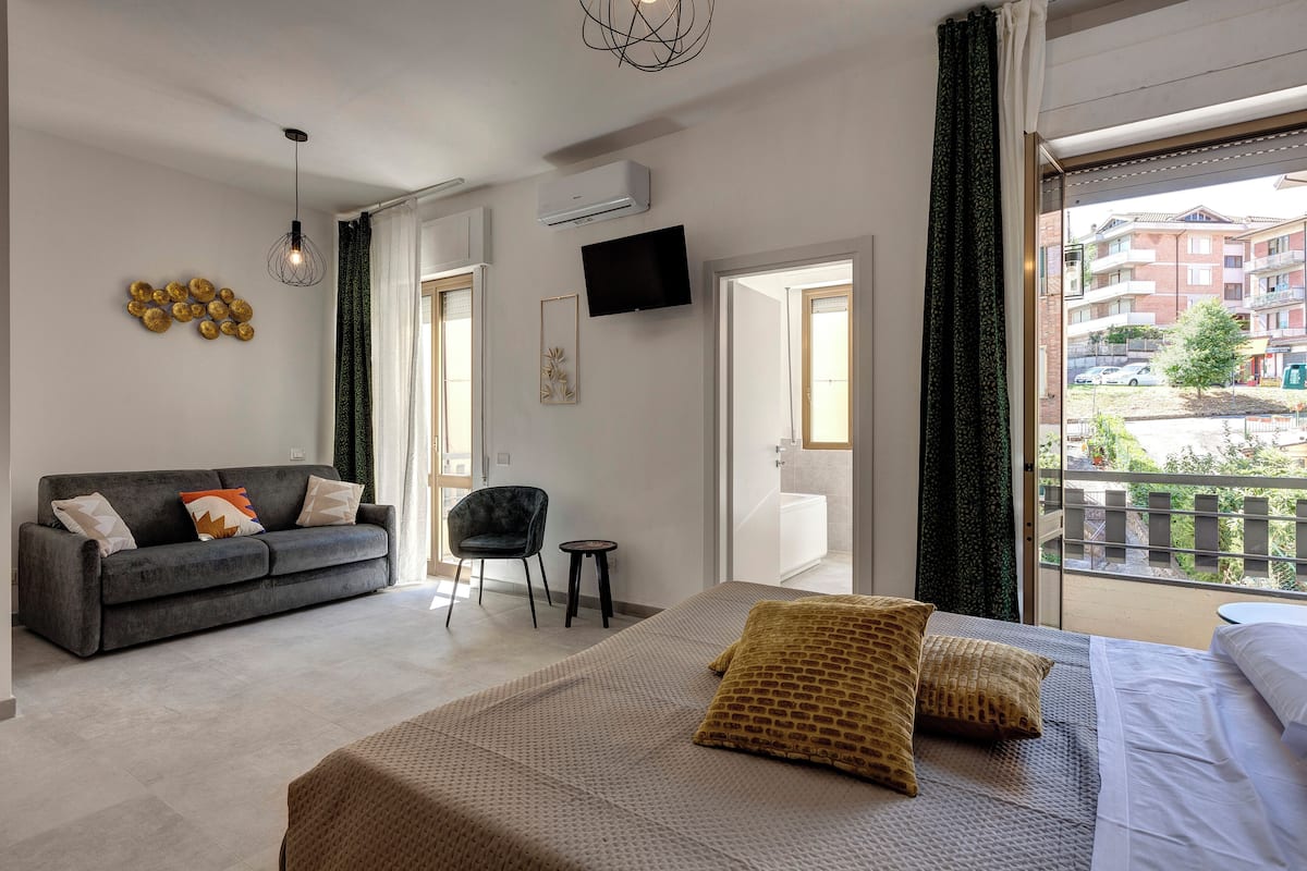 Une chambre d’hôtel moderne dotée d’un grand lit, d’un canapé, d’une télévision et d’un balcon offrant une vue sur la ville.