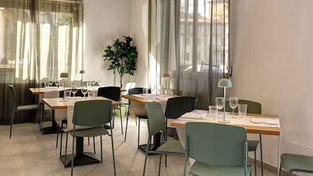 A dining area with tables set for four, chairs, and a potted plant. - Palazzo Belvedere Chianciano Terme (Chianciano Terme)