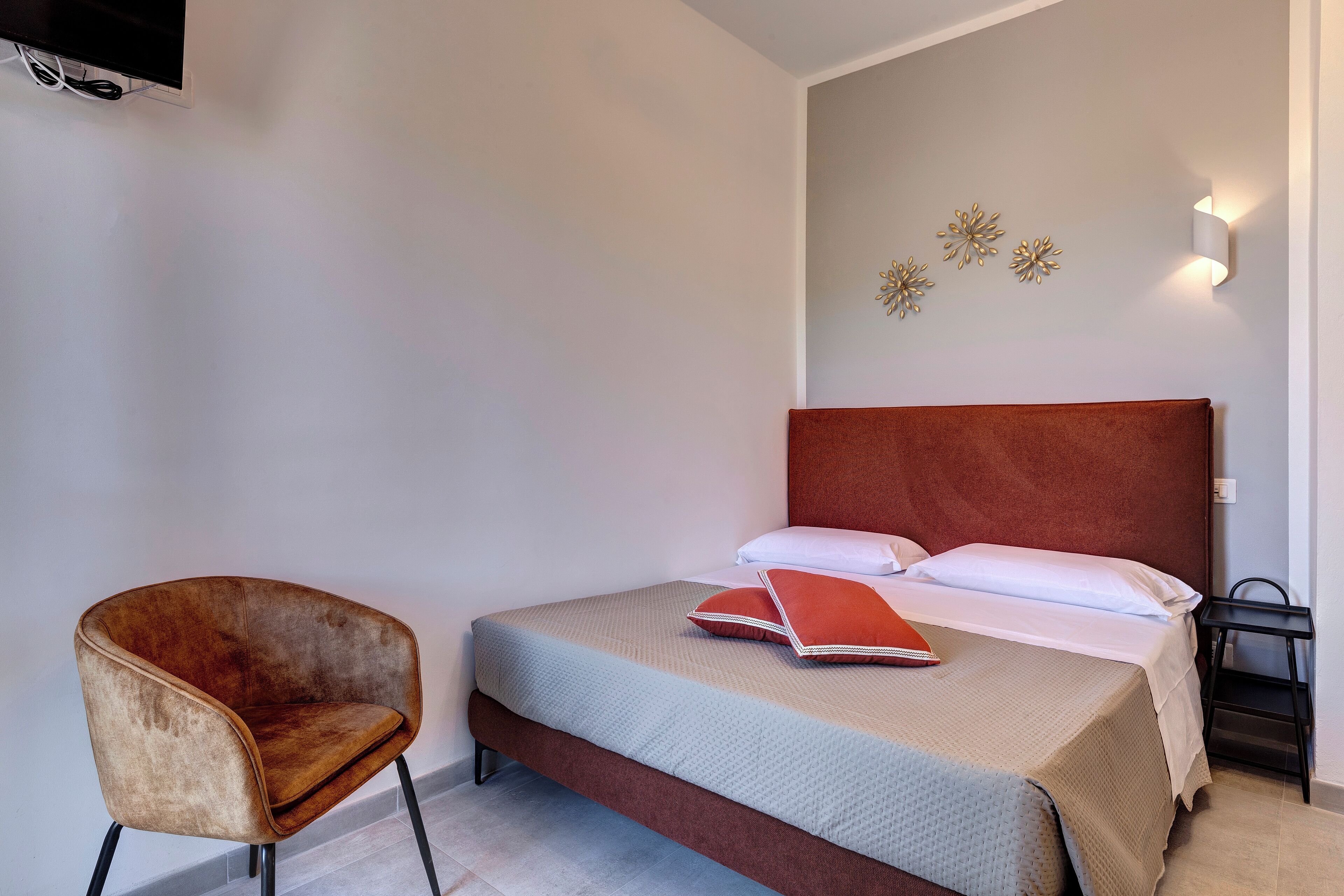 A bedroom with a bed, a chair, a bedside table, and wall decorations.