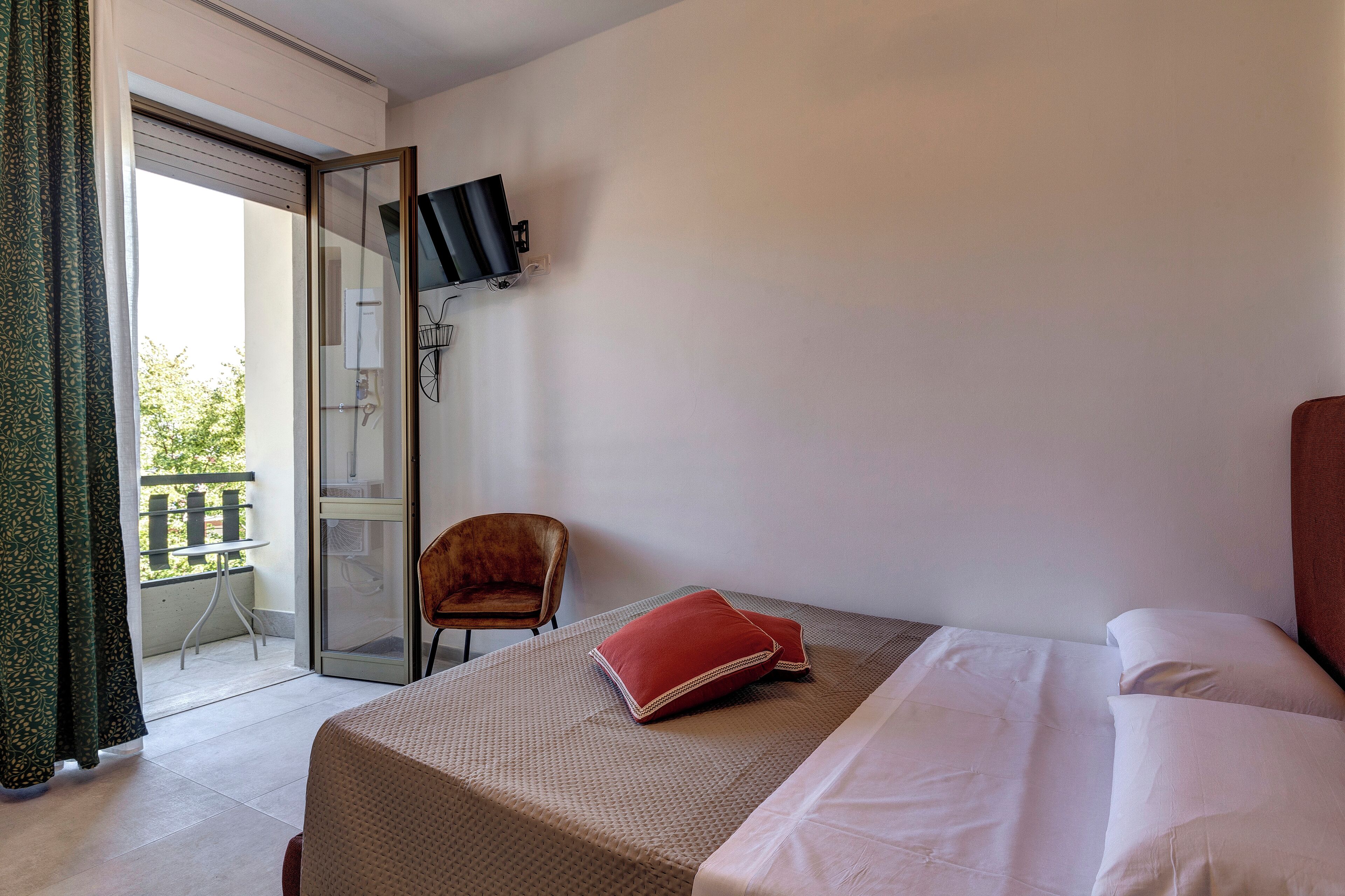Une chambre d’hôtel avec un lit, une chaise, un téléviseur fixé au mur et un balcon avec vue.