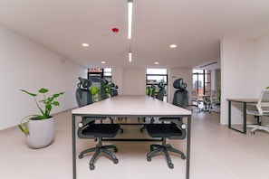A conference room with a long table, multiple chairs, and potted plants.