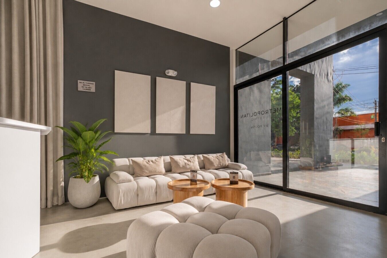 A modern living room with a sofa, two coffee tables, and a large window.