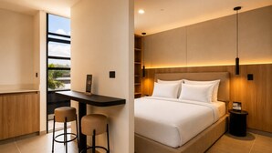 A modern hotel room with a bed, a desk with two stools, a small table, and a nightstand. - Stylish Studio with Cowork, Gym and Jacuzzi`s (Medellín)