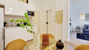 Una cucina moderna con mobili bianchi, un forno a microonde e una pianta sul ripiano.