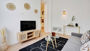 Un soggiorno moderno con televisione a schermo piatto, mobile TV in legno, tavolino in vetro e un divano grigio.
