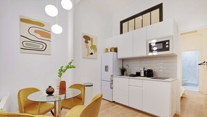 Una cucina moderna con mobili bianchi, un forno a microonde e un'area pranzo con sedie gialle e un tavolo in vetro.