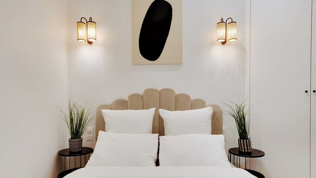 Una camera da letto moderna con un letto grande, due comodini con lampade, un elemento decorativo a parete e un armadio.