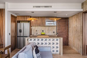 A modern kitchen with a built-in refrigerator, wooden cabinets, and pendant lighting.