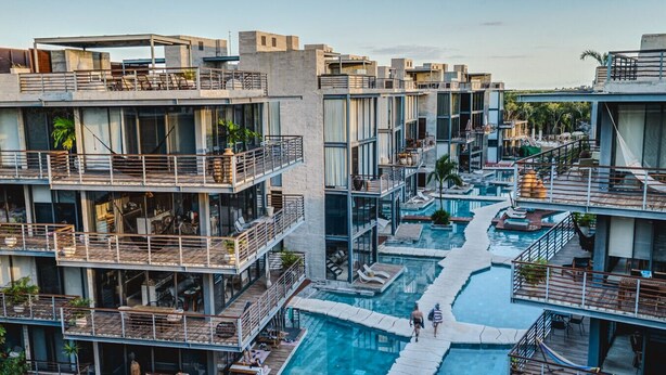 Un hotel a più piani con piscina centrale, balconi con posti a sedere all'aperto e vista sui dintorni.