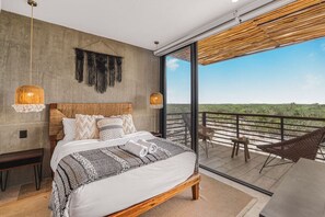 A bedroom with a large bed, a balcony with a view, and a hanging light fixture.