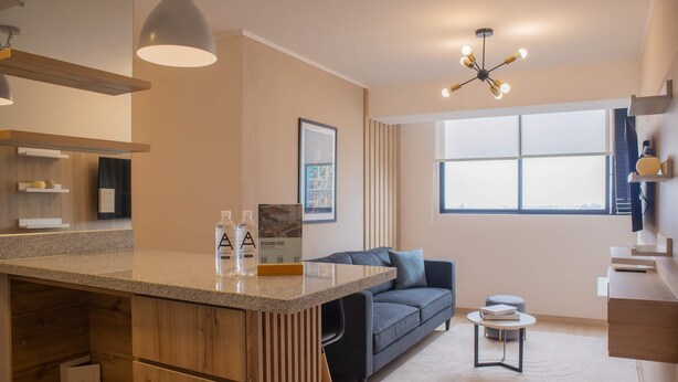 A modern kitchen with a central island, a dark grey sofa, and a small round table. - w Cozy Bright 2BR Stay in Barranco (Lima)