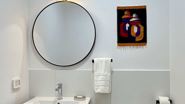 A modern bathroom with a round mirror, a white sink, a toilet, and a trash bin. - w Trendy 2BR Duplex Retreat in Cusco (Cusco)