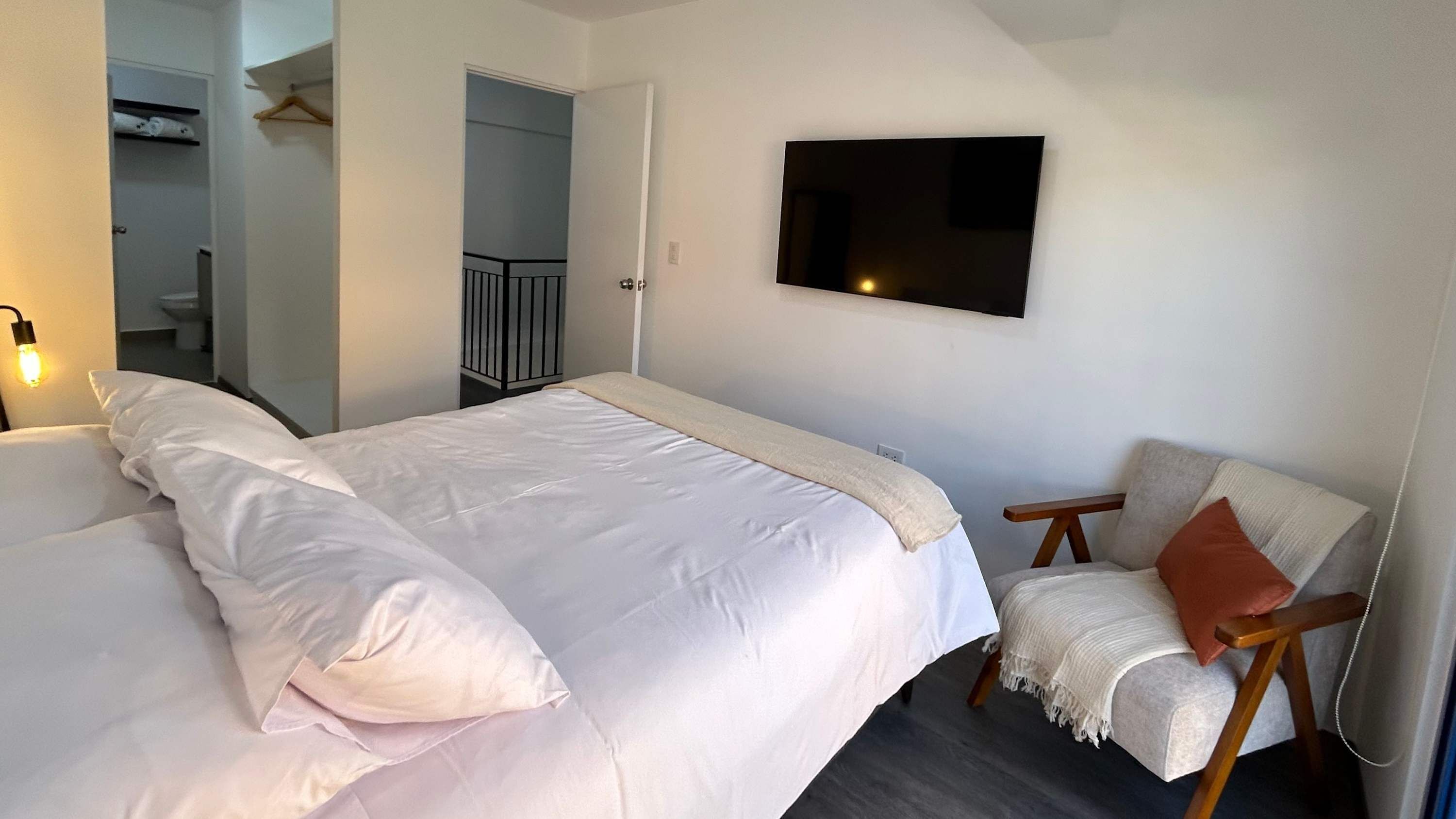 Een slaapkamer met een bed, een stoel, een televisie en een deur naar een badkamer.