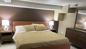 A bedroom with a large bed, two bedside tables with lamps, a dresser, and a mirror. - Mid-Century Modern Broad Ripple Stay with Style, Comfort & Local Color (Indianapolis)