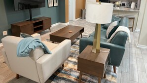 A living room with a sofa, coffee table, TV, and a lamp. - Mid-Century Modern Broad Ripple Stay with Style, Comfort & Local Color (Indianapolis)