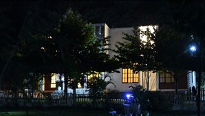 A building with a large window and a visible door, surrounded by trees and a fence. - PUMZIKA HILL CAMPSITE (Kisongo)