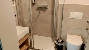 A bathroom with a shower, toilet, and sink.