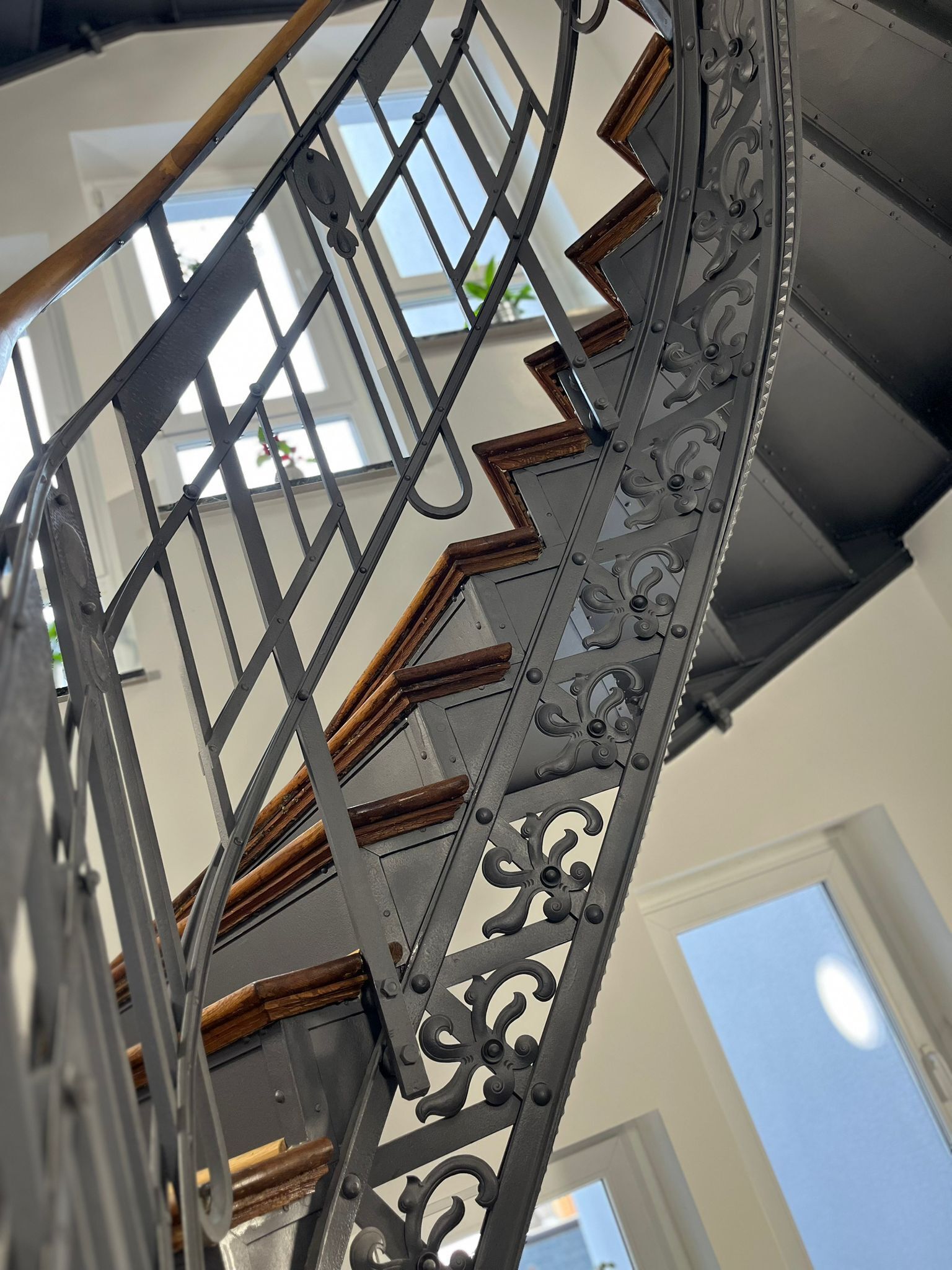 Eine Treppe mit aufwendiger Metallreling und Holzstufen.